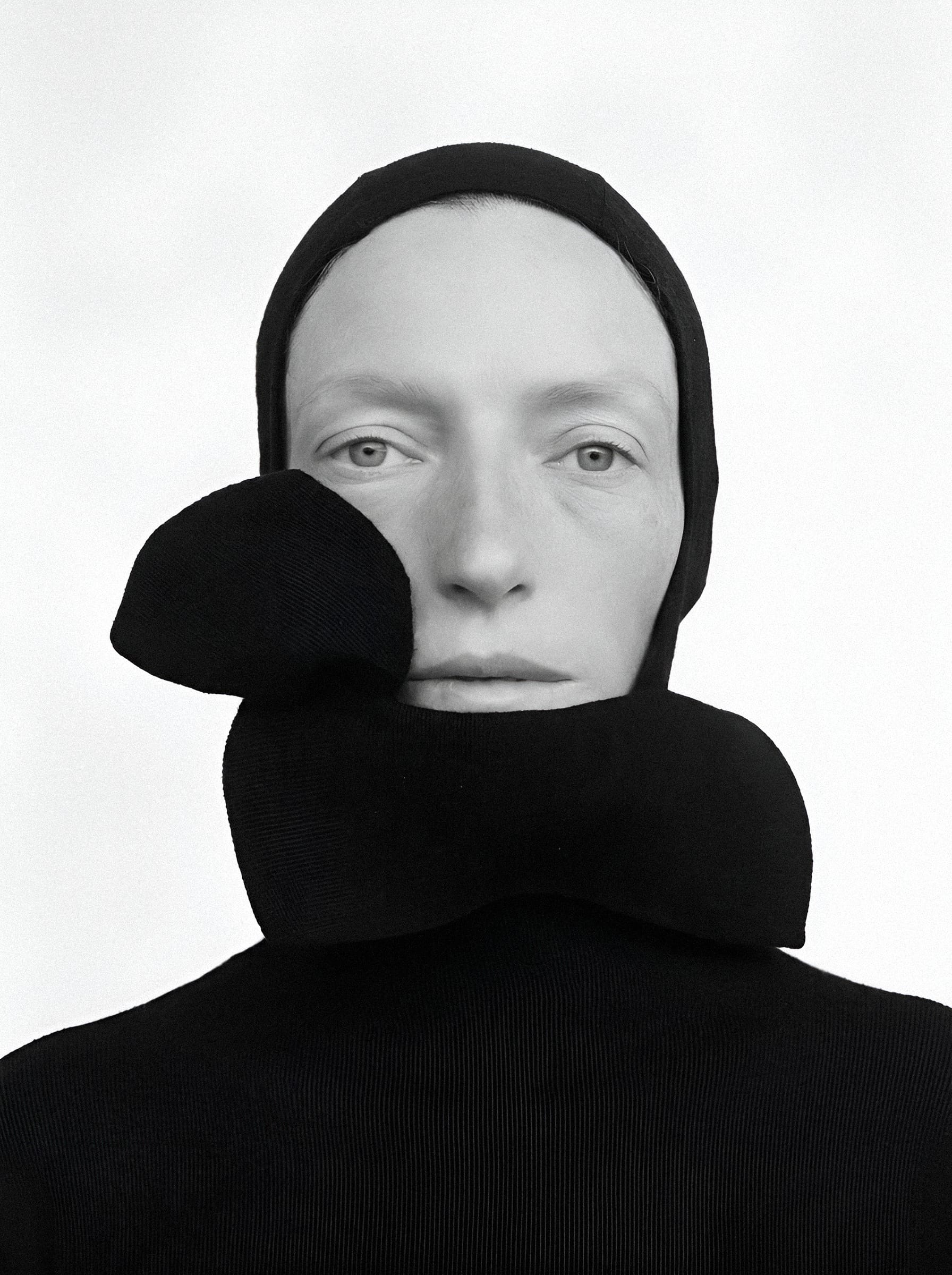 Figure in black knit with draped collar.