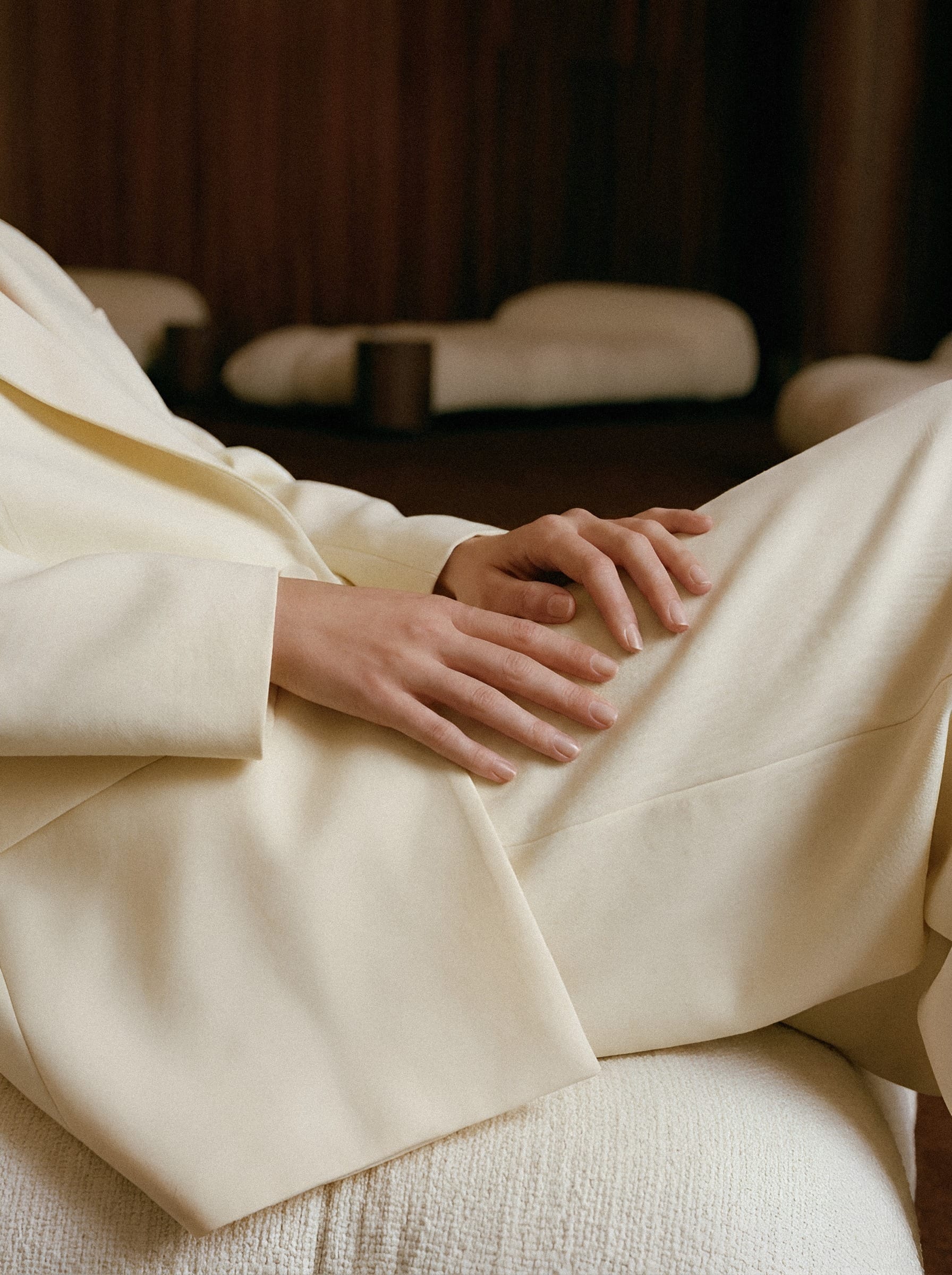 A hand resting against softly gathered cream fabric.